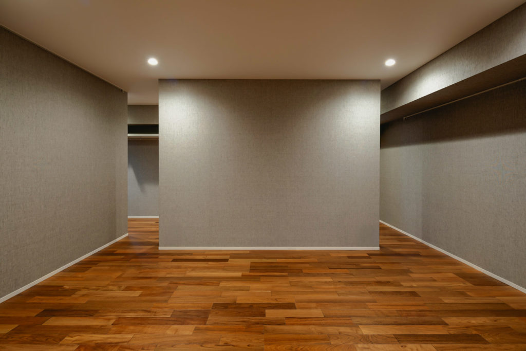 H RESIDENCEの寝室。落ち着いたグレーの壁紙と無垢フローリング、間接照明で演出されたシンプルかつ落ち着きのあるプライベート空間。（設計監理：an DeSign & Associates）