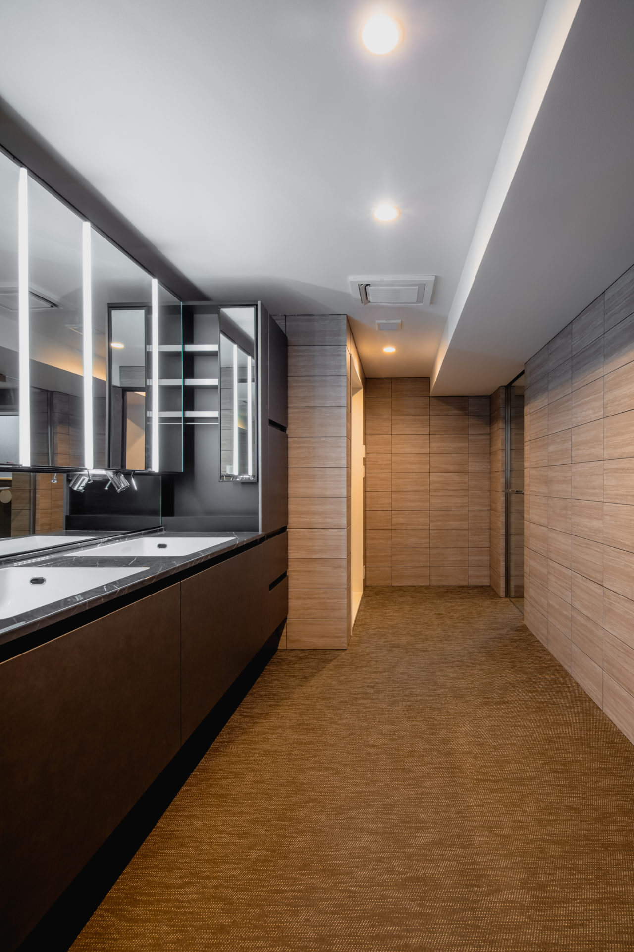 H RESIDENCEの洗面脱衣室。ライムストーンの壁と落ち着いた床材で仕上げたホテルライクなサニタリースペース。（設計監理：an DeSign & Associates）