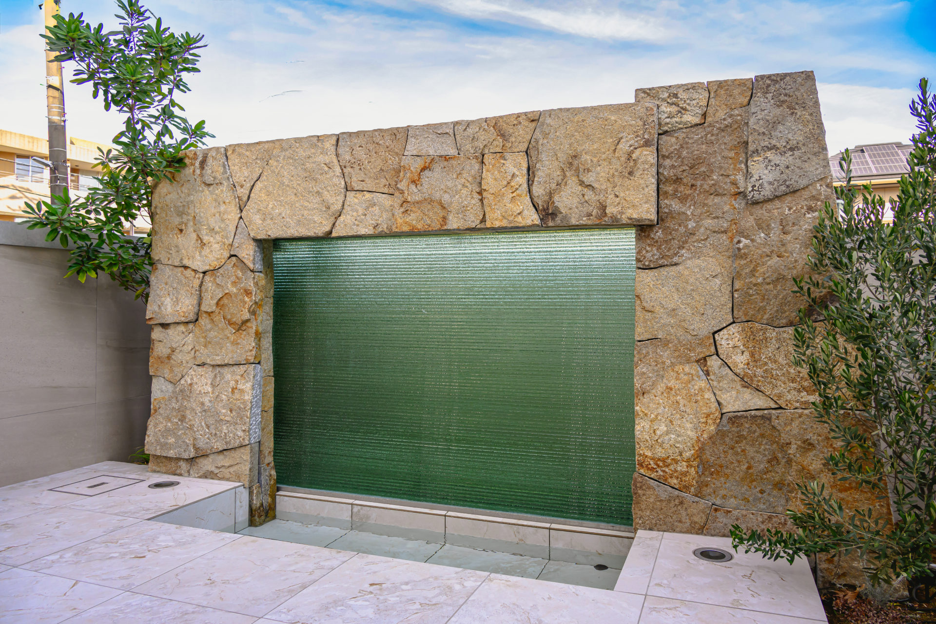 H RESIDENCEの中庭。石張りの床と水盤を配した都市型住宅の外部空間。